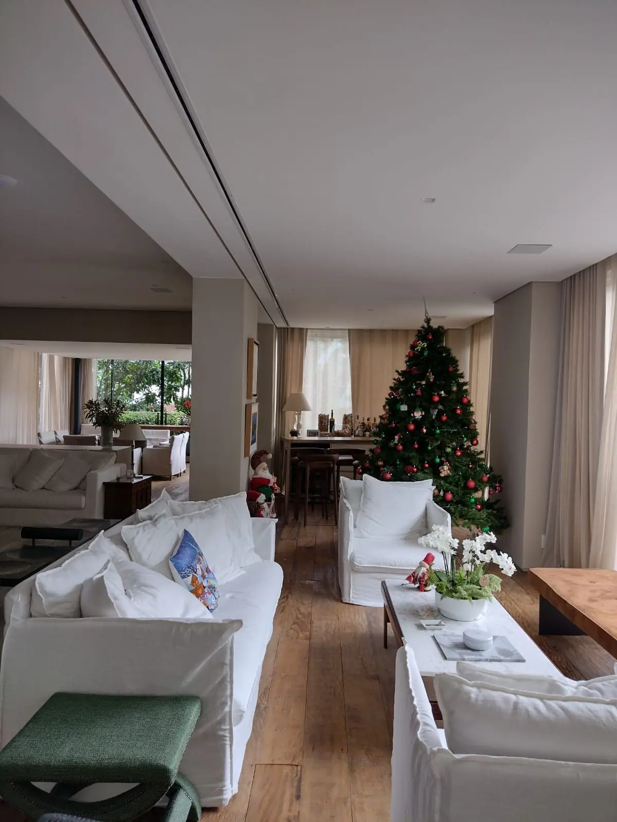 Long linear diffuser recessed into a ceiling above a living area with white sofas and wood flooring