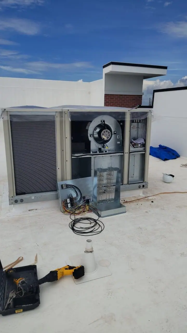 Rooftop package unit with its panels open and tools on the roof